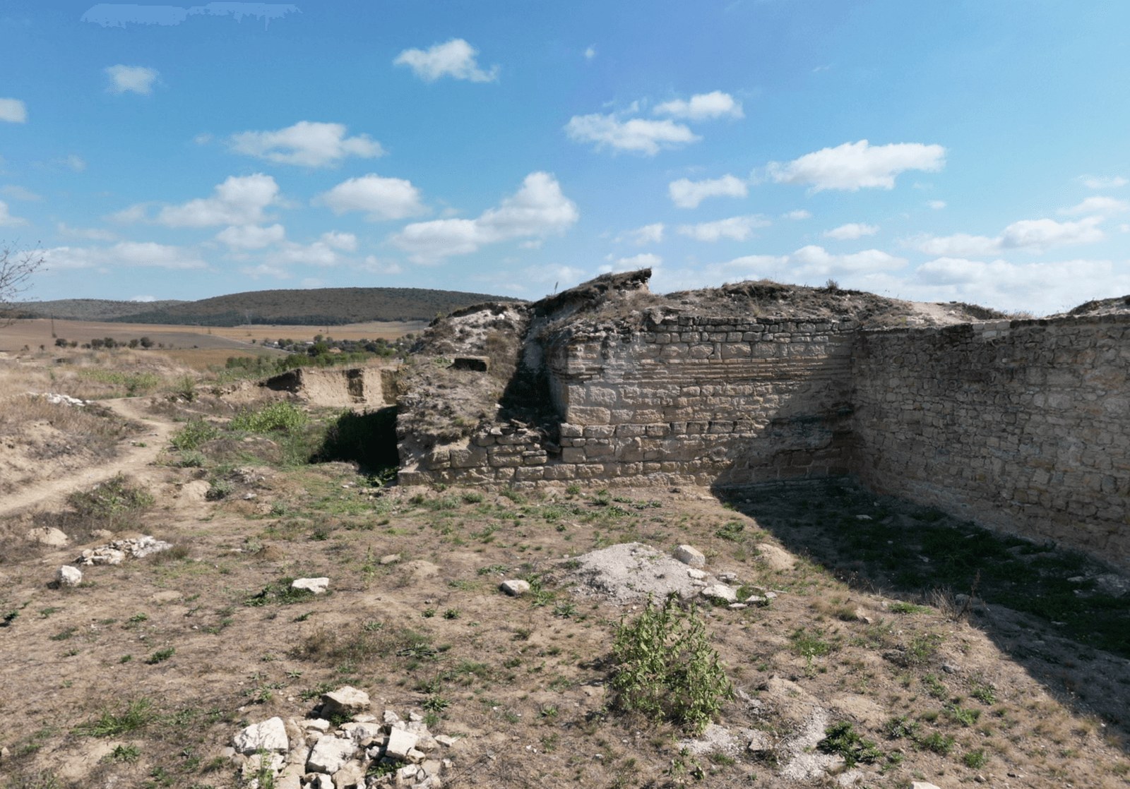 Ruine vechi pe câmpie sub cer senin.
