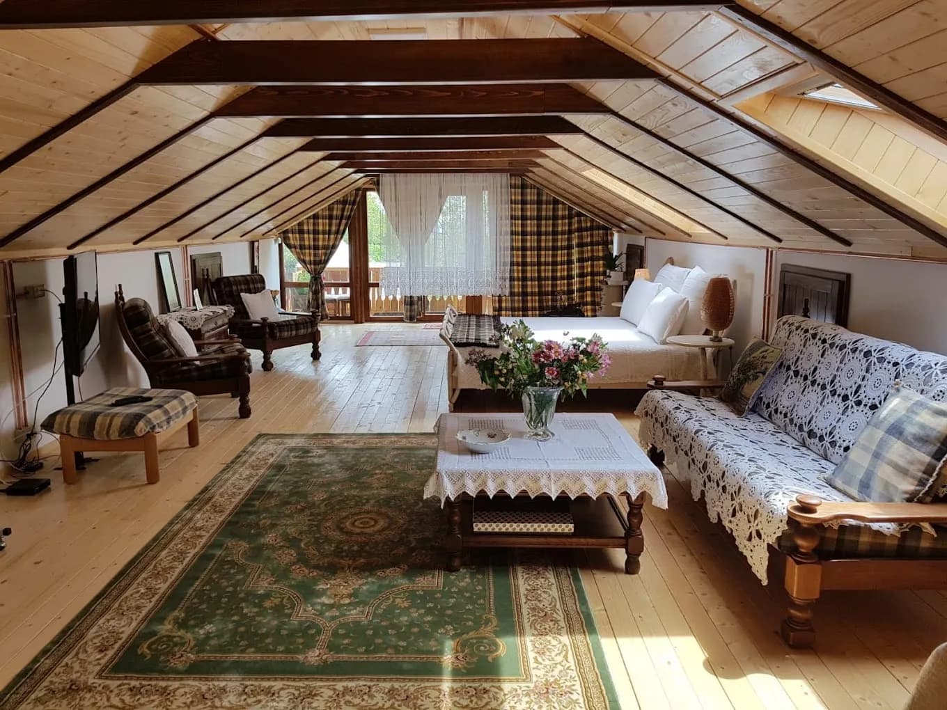 Mansardă rustică cu mobilier din lemn și canapea decorativă.