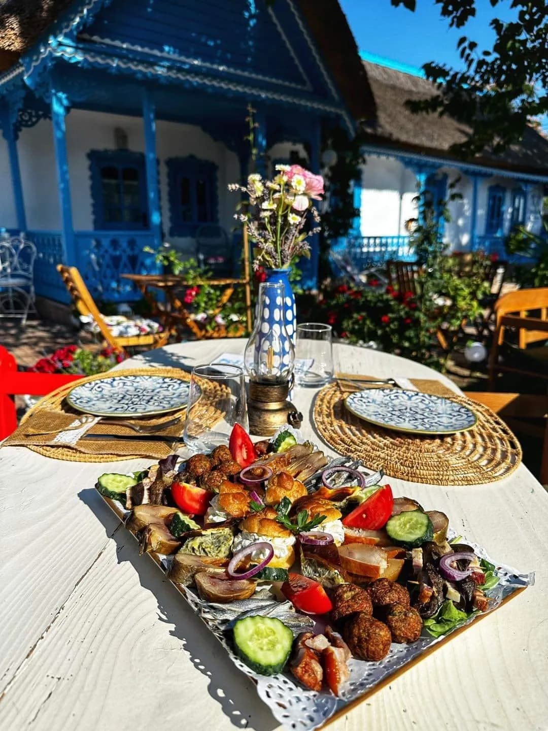 Masă tradițională românească în curte cu casă albastră