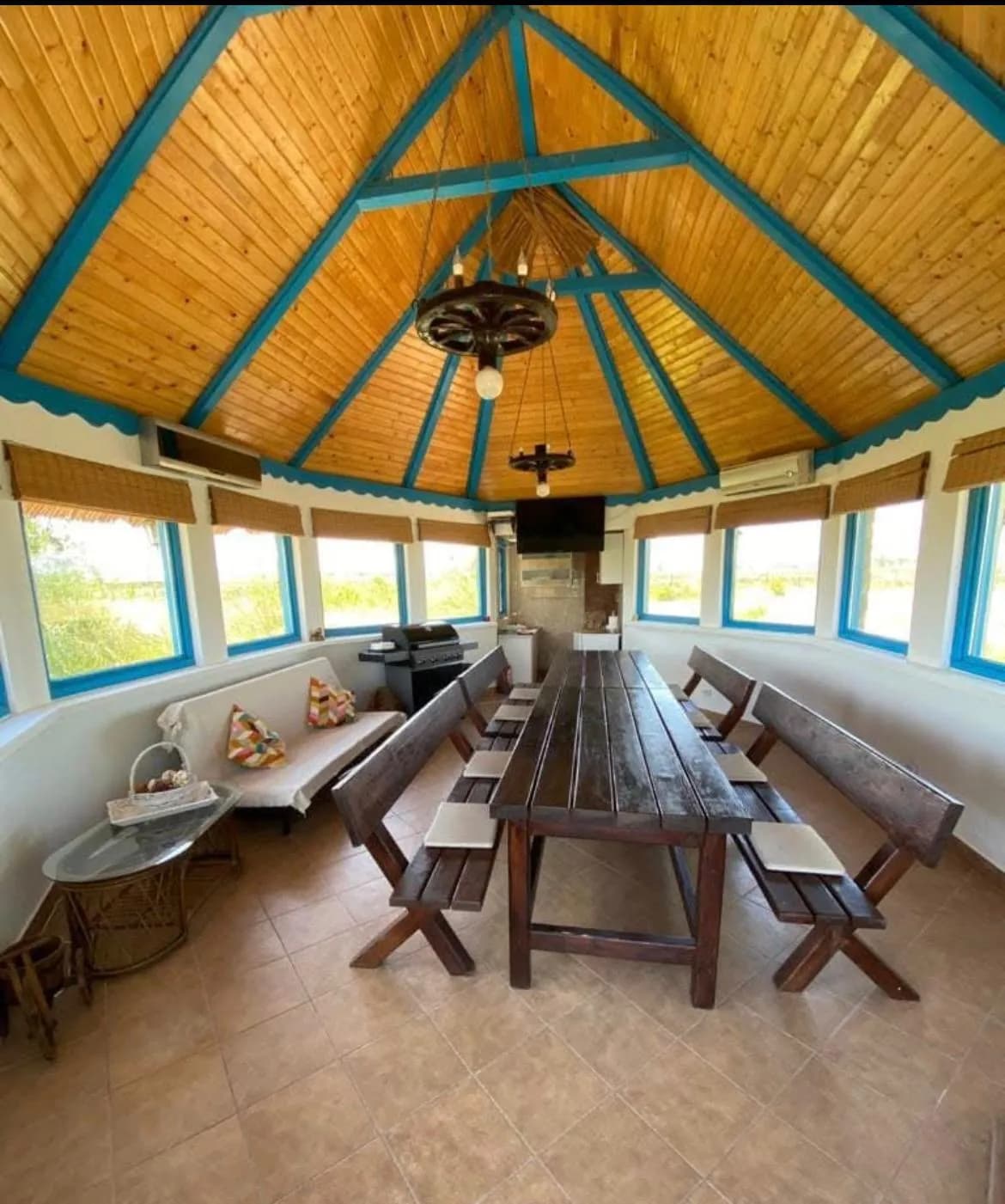 Foișor din lemn cu masă și banci, interior rustic.