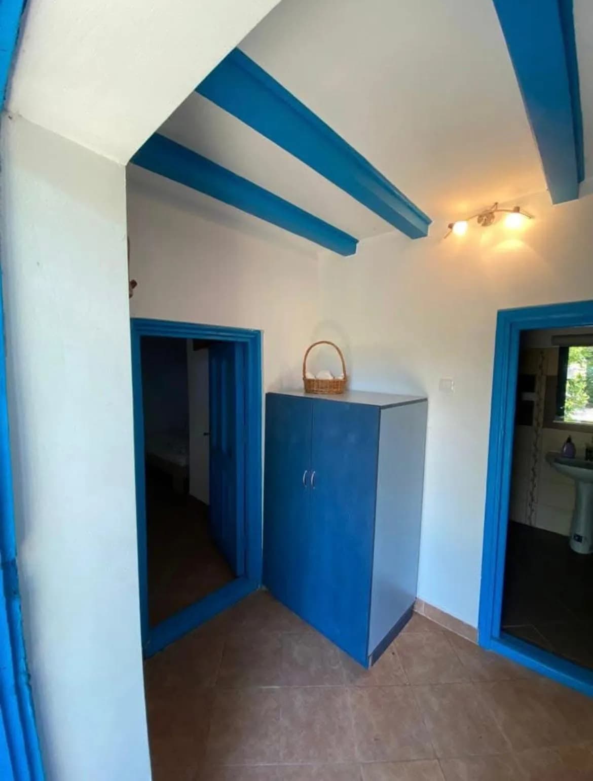 Hol luminos cu dulap albastru și coș decorativ