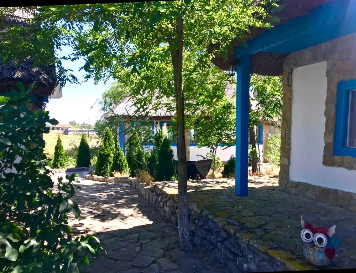 Curte tradițională cu case și copaci umbrosi.